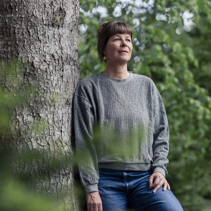 Sandra Baumann angelehnt an einen Baum im Wald