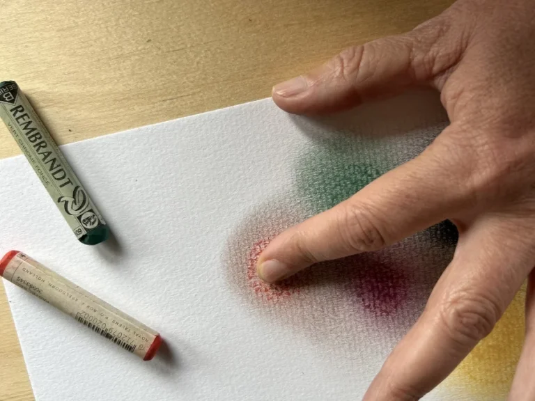 Pastellkreide wird auf einem Blatt Papier mit dem Finger verwischt