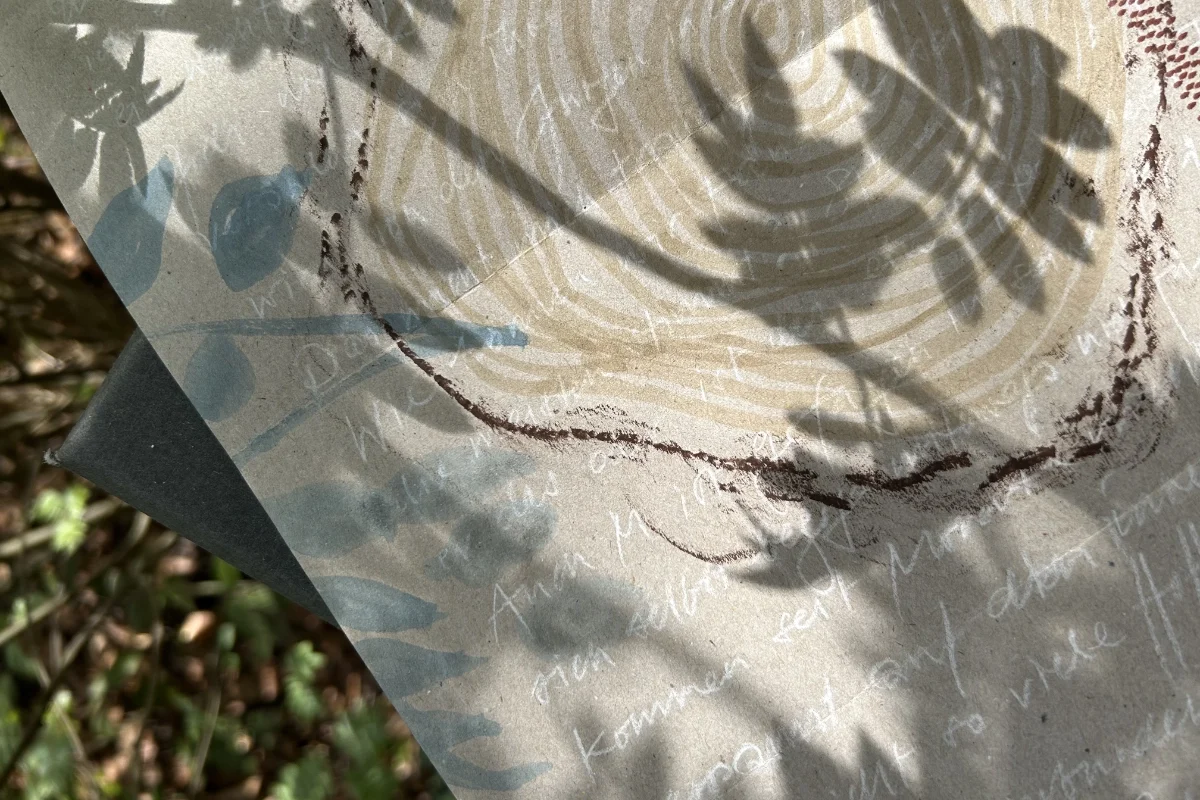 Auf dem Waldboden liegt ein gestaltetes Blatt Papier.